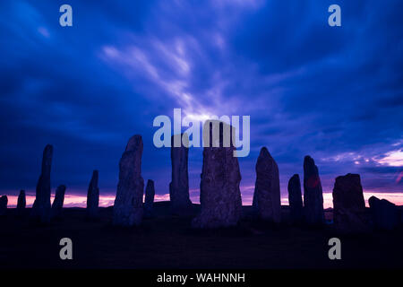 Silhouette dell'antica Callanish Standing Stones, contro un drammatico cielo nuvoloso al tramonto, Calanais, Ebridi Esterne, isola di Lewis, Scotland, Regno Unito. Foto Stock