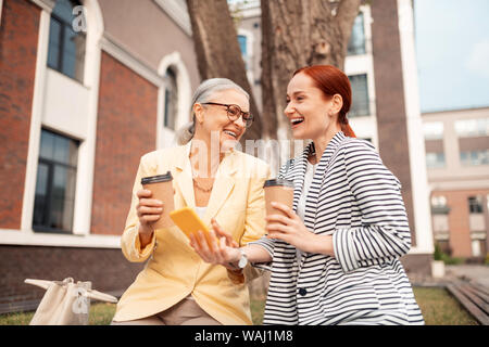 Due belle eleganti i colleghi seduti all'aperto mentre ridono Foto Stock