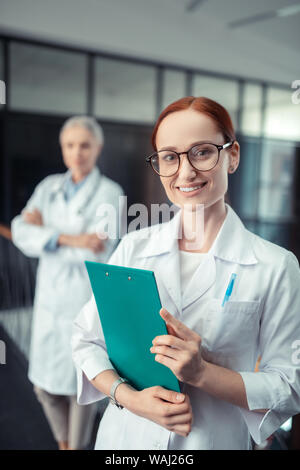 Donna sorridente medico cercando di fronte a lei Foto Stock