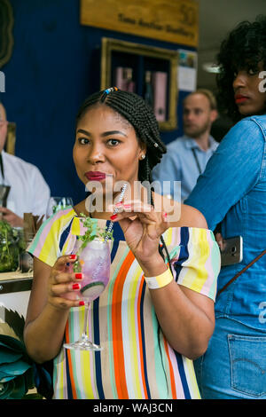 Johannesburg, Sud Africa - 14 Ottobre 2017: donna africana sorseggiando un cocktail e generalmente godendo di una giornata in un cibo e Fiera del Vino Foto Stock