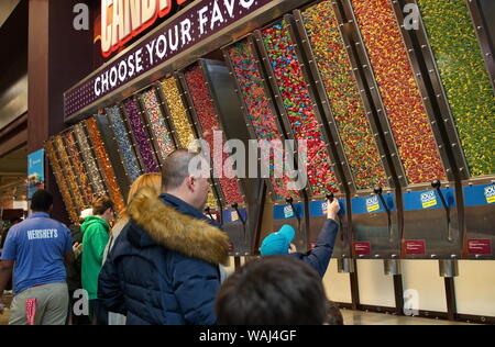 Hershey PA, Stati Uniti d'America. Mar 2019. Mamma e papà guardando come eccitato figlio eroga la caramella in un sacco bottino. Foto Stock