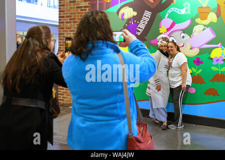 Hershey PA, Stati Uniti d'America. Mar 2019. Gli amici e la famiglia in posa e tenendo il cellulare foto al mondo del cioccolato. Foto Stock