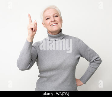 Perfetta idea. Donna anziana puntare il dito verso l'alto, ha ottenuto la soluzione del problema Foto Stock