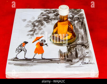 Phnom Penh Cambogia. Il vino di riso in plastica con il modello di serpente cobra venduto come un souvenir seduto su di un dipinto di un locale rurale scena cambogiano. (Solo uso editoriale) Foto Stock