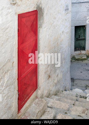 Vicolo con una porta rossa e una verde porta nella città vecchia di Ostuni. Foto Stock