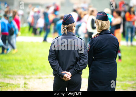 La regione di Celjabinsk, Russia - Giugno 2019: femmina ufficiali di polizia sono guardando l'affollamento. Due unidentified polizia russa delle donne in uniforme il monitor Foto Stock
