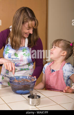 Madre e figlia di ridere mentre la miscelazione la torta di carote ingredienti. (MR, PR) Foto Stock
