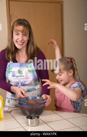 Madre di miscelazione torta di carote di pastella, mentre la figlia di cinque anni orologi e finge di essere un mostro. (MR, PR) Foto Stock