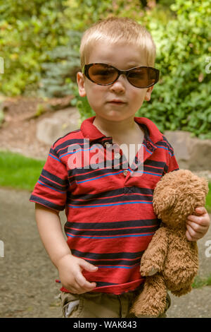 Issaquah, nello Stato di Washington, USA. Bimbo di 2 anni che trasportano orsacchiotto e indossando occhiali da sole. (MR) Foto Stock