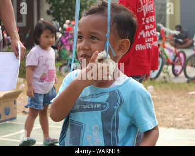 Bambini mangiare crackers di concorrenza, celebrazione dell Indonesia 74a giorno di indipendenza Foto Stock