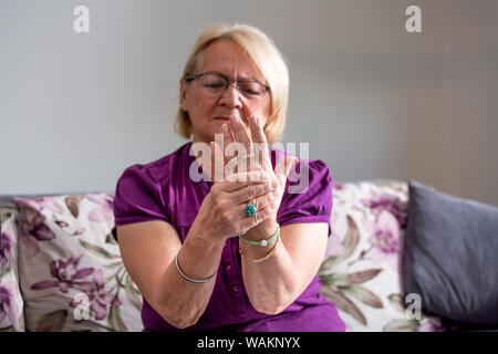 Donna anziana che soffre di dolore in mano, artrite persona vecchia e senior donna donne che soffrono di dolore a casa Foto Stock