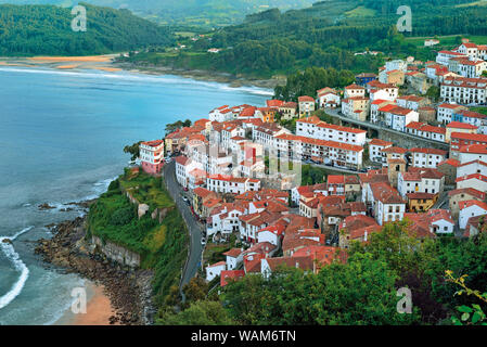 Vista del piccolo villaggio costiero con il verde delle montagne e spiagge di sabbia Foto Stock