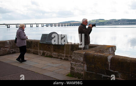 Dundee, Tayside, Scozia, Regno Unito, 21 Agosto, 2019. Regno Unito meteo: un giorno nuvoloso con alcuni incantesimi soleggiato, temperatura massima 19°C. I turisti il giorno fuori sulla città di Dundee waterfront ammirando la vista della calma argenteo fiume Tay con gli anni sessanta Tay road bridge in distanza. Credito: Dundee fotografico / Alamy Live News Foto Stock