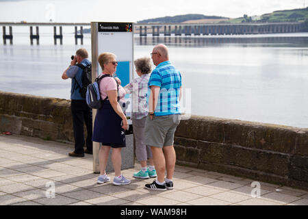 Dundee, Tayside, Scozia, Regno Unito, 21 Agosto, 2019. Regno Unito meteo: un giorno nuvoloso con alcuni incantesimi soleggiato, temperatura massima 19°C. I turisti il giorno fuori sulla città di Dundee waterfront ammirando la vista della calma argenteo fiume Tay con gli anni sessanta Tay road bridge in distanza. Credito: Dundee fotografico / Alamy Live News Foto Stock