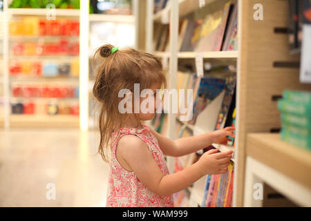 Poco carino bambino la raccolta di libri da scaffale in book store Foto Stock