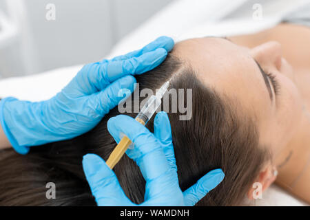 Estetista iniezioni per una sana crescita dei capelli. La mesoterapia del cuoio capelluto. Una giovane ragazza sta subendo un corso di trattamenti termali in ufficio di un beau Foto Stock