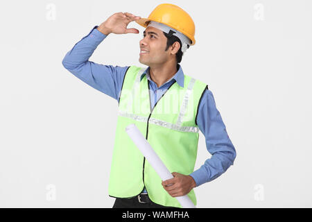 Architetto tenendo un blueprint e guardando in alto Foto Stock