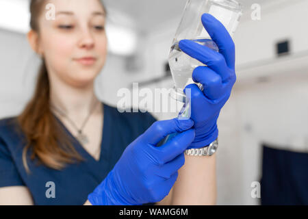 Giovane infermiere professionale medica uniforme, mostra una siringa nelle sue mani a sfondo di ambulanza. Foto Stock