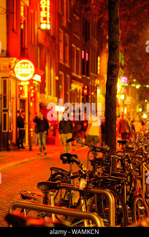 Le Biciclette parcheggiate e pedoni sulla banca Canale di Beagle notte strade del quartiere a luci rosse di Amsterdam Foto Stock