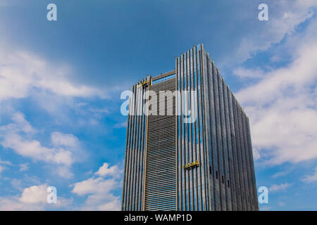 I lavoratori in una culla di appendere il lavaggio di windows in un edificio alto Foto Stock