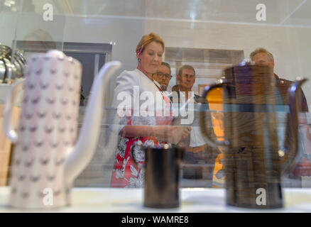 21 agosto 2019, Brandeburgo, Eisenhüttenstadt: Franziska Giffey (SPD, l), Ministro federale per gli Affari Familiari, guarda al caffè pentole in una mostra presso il Centro di Documentazione per la cultura della vita quotidiana nella RDT. All inizio del suo viaggio estivo, il Ministro federale degli affari di famiglia ha visitato Eisenhüttenstadt nell est del Brandeburgo e imparato di più della storia della RDT del primo socialista pianificata città durante un tour della citta'. Foto: Patrick Pleul/dpa-Zentralbild/dpa Foto Stock