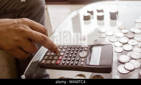 Immagine ritagliata di imprenditore contare monete utilizzando la calcolatrice a scrivania in ufficio. Commercianti lato contare monete. Finanza aziendale e risparmio Inves Foto Stock