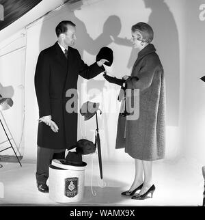 Christys' cappelli di Londra. Un giovane è fotografato in un studio di indossare il cappotto. Essi stanno cercando di cappelli fuori dalla società inglese Christy a Londra, fondata 1773. La Svezia 1958. Foto Kristoffersson Ref CC62-2 Foto Stock