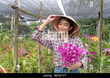 Il giardiniere dispone il giardino di orchidee tenendo il cappello. E tenendo le orchidee nel giardino di orchidee Foto Stock