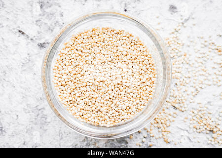 Bianco di grani di quinoa su sfondo grigio. Cibo sano. Vista dall'alto. Foto Stock