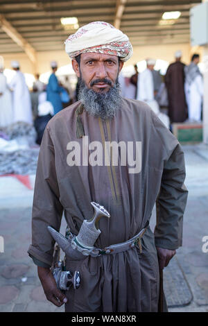 Uomo in abiti tradizionali con un khanjar (pugnale) incollata sulla cinghia a Sinaw mercato, Oman Foto Stock