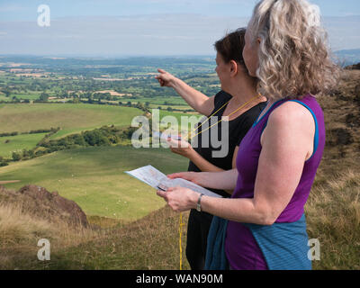 Due donne su un corso di abilità all'aperto che impara la navigazione per mappa e bussola nelle colline di Shropshire, Regno Unito Foto Stock