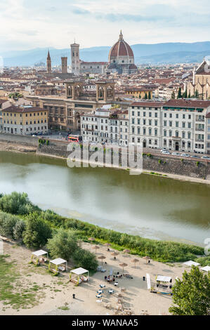 Lettini da mare e ombrelloni sulla riva del fiume Arno urban beach. Paesaggio urbano di Firenze con la Basilica di Santa Maria del Fiore, il Campanile di Giotto, Biblioteca Nazionale Centrale. Foto Stock