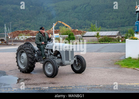 L'uomo verde tuta impermeabile la Guida 1956 Grigio Vintage Massey Ferguson Grey Fergie trattore anteriore maschio fuorigioco driver vista laterale veterano luccicanti Loc Santa Foto Stock