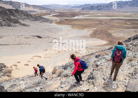 Mongolia Ulgii 2019-05-04 gruppo turistico escursioni e arrampicate unitamente alla guida, scendendo dalla cima della montagna. Vista posteriore. Concetto di libertà, zainetto Foto Stock