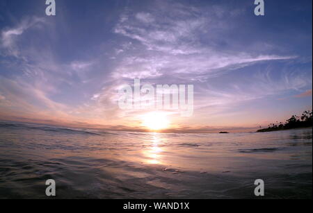 Vivace tramonto riflesso dalla oleoso oceano liscia superficie POV IN ACQUA Foto Stock