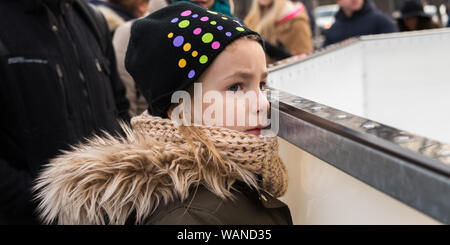 Vienna, Austria - 10 dicembre 2017: Triste bambina a guardare la gente pattinare sul ghiaccio nel parco Foto Stock