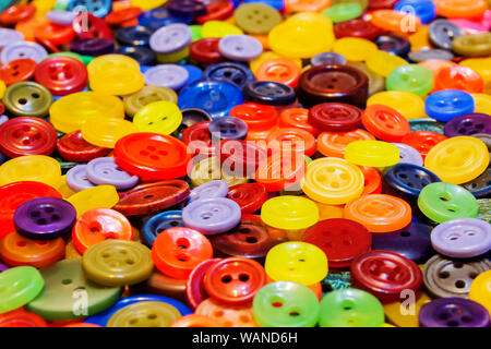 Sfondo - casualmente disperse multicolore di cucire attraverso i pulsanti di diverse sfumature e dimensioni Foto Stock