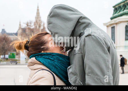 Vienna, Austria - 10 dicembre 2017: La ragazza sorride al misterioso ragazzo che ha un cappuccio sulla sua testa Foto Stock