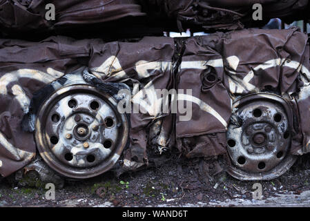 Vecchio arrugginito vetture frantumato (automobili) con auto Ruote, pneumatici (pneumatici) e parti di automobili ruggine in un scrapyard con urban graffiti tagging textu in background Foto Stock