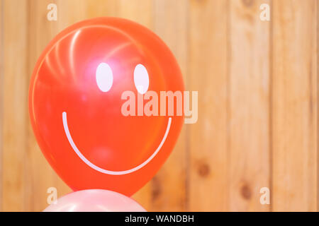 Sorriso palloncino rosso nella parte anteriore del legno verticale della piastra di sfondo qualsiasi Happy Card. Foto Stock