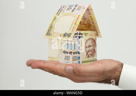 Agente immobiliare che tiene una casa modello fatta di cinquecento rupie nota Foto Stock