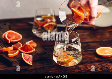 Versando acqua infusa con sanguinosa arance in vetro Foto Stock