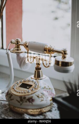 Primo piano verticale selettivo di un lussuoso bianco e oro telefono retro Foto Stock
