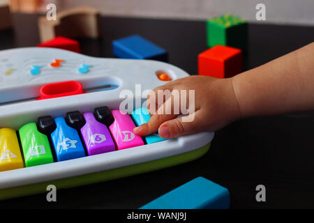 Baby di giocare e imparare con un pianoforte giocattolo. Foto Stock