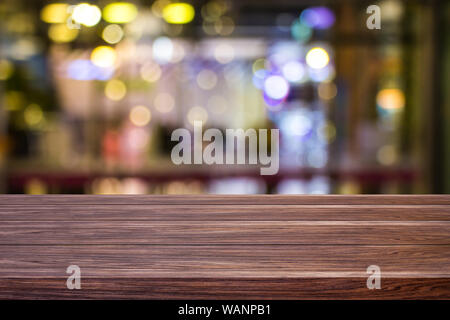 Blur cafe ristorante o negozio di caffè vuota di legno scuro tavolo con luce sfocata gold bokeh sfondo astratto per montaggio display del prodotto o il design. Foto Stock