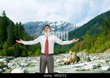 Uomo d'affari spensierato in piedi con il braccio teso, Beas River, Manali, Himachal Pradesh, India Foto Stock