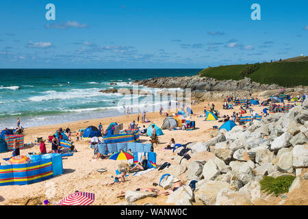 I turisti in vacanza in vacanza su una soleggiata spiaggia Fistral a Newquay in Cornovaglia. Foto Stock