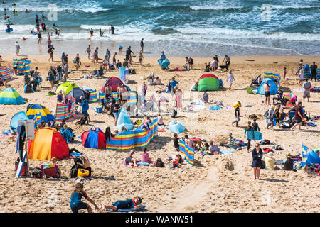 I turisti su un soleggiato Fistral Beach in Newquay in Cornovaglia. Foto Stock