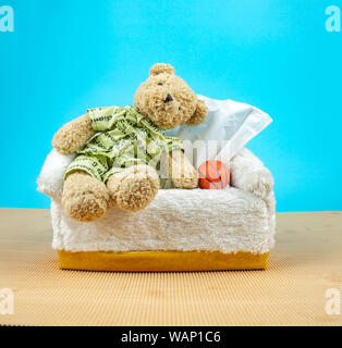 Orsacchiotto di peluche indossare il pigiama e sedersi sulla casella di tessuto con basket accanto Foto Stock