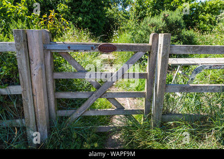 Azienda privata terreno recintato da un grande cancello con un privato di tenere fuori segno indicante nessun accesso al percorso rurale Foto Stock